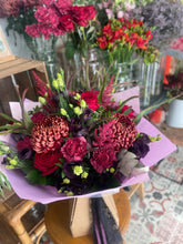 Load image into Gallery viewer, luxury bouquet of red and purple flowers on a table displayed in front of a stand of flowers at Bits and Buds florist in leighton buzzard halloween autumn arrangement