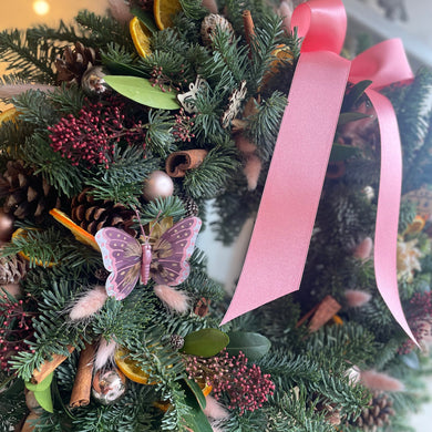 a pink and green luxury Christmas wreath with a pink satin bow from Bits and Buds florist in Leighton Buzzard close up details and butterfly