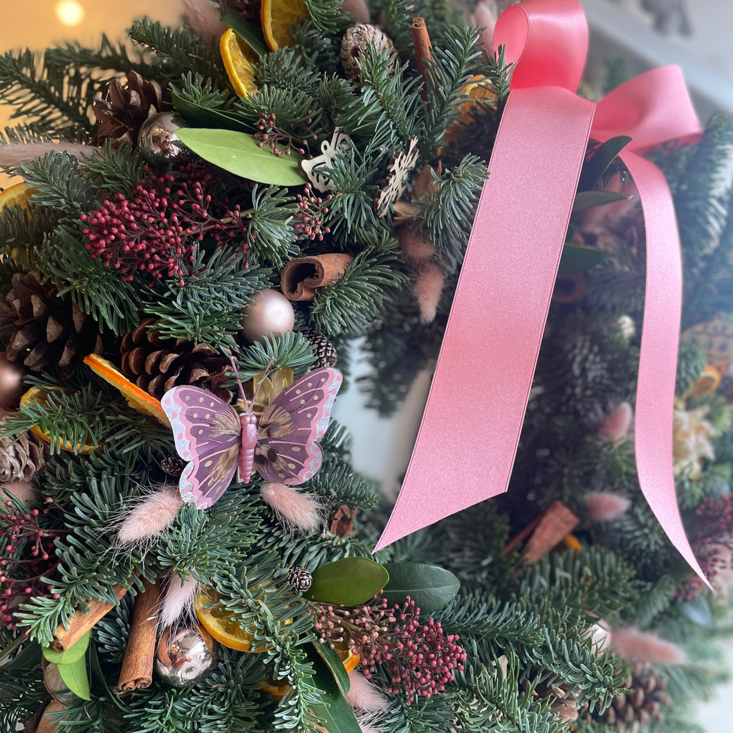 a pink and green luxury Christmas wreath with a pink satin bow from Bits and Buds florist in Leighton Buzzard close up details and butterfly
