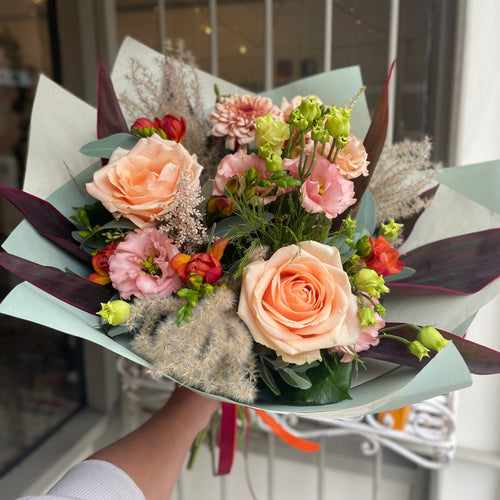 autumnal bouquet with dried pampas grass ad roses held by a florist at bits and buds flower shop in leighton buzzard bedfordshire 