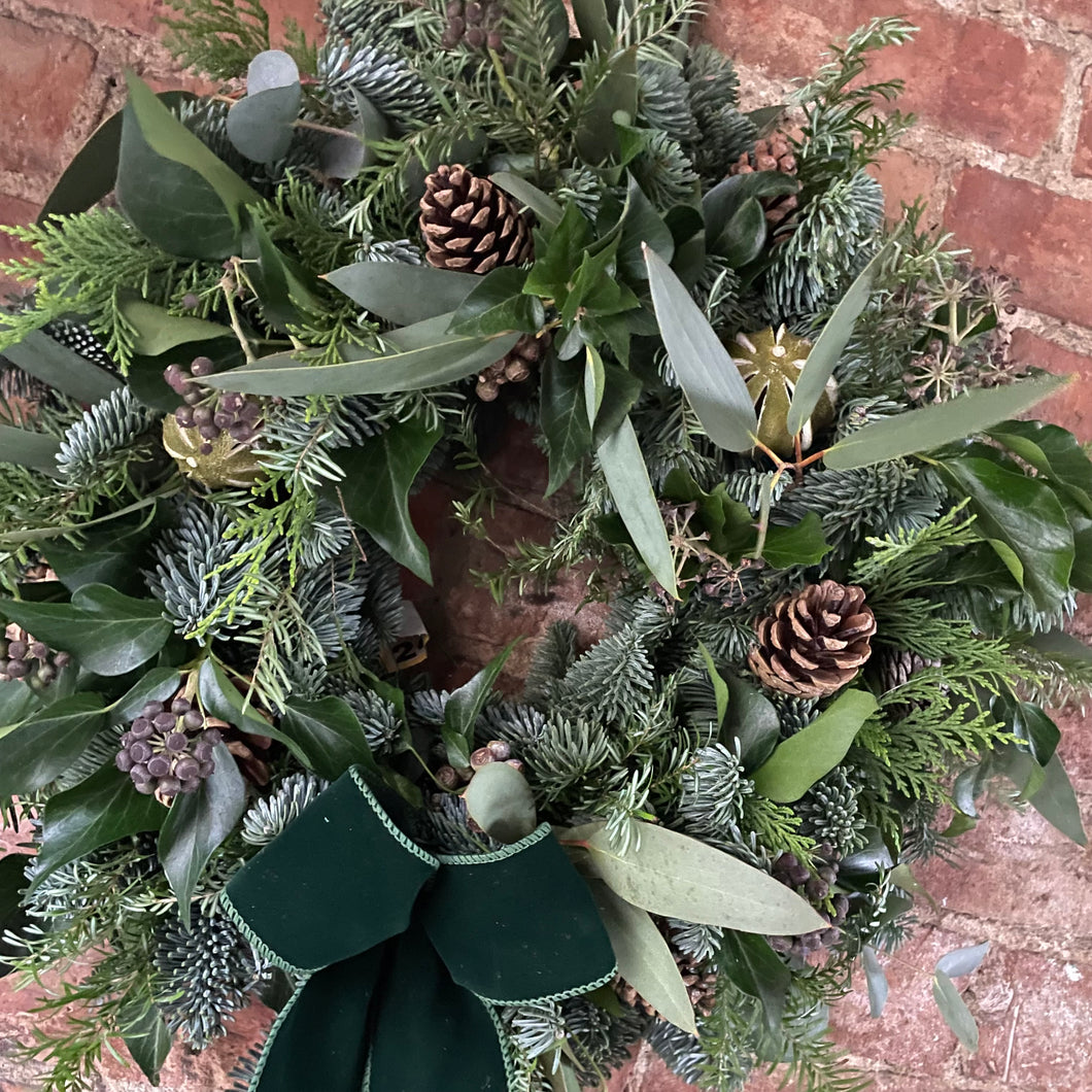 an all green Christmas wreath with a luxury velvet bow
