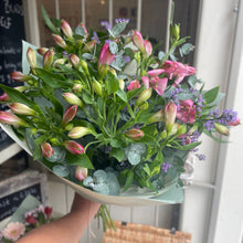 Load image into Gallery viewer, bouquet of alstromeria flowers wrapped in eco friendly paper for friendship and love. long lasting flowers from bits and buds florist in leighton buzzard held up on the doorstep with the shop in the background.
