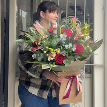 Load image into Gallery viewer, florist carrying a big luxury bouquet on the doorstep of bits and buds flower shop in leighton buzzard
