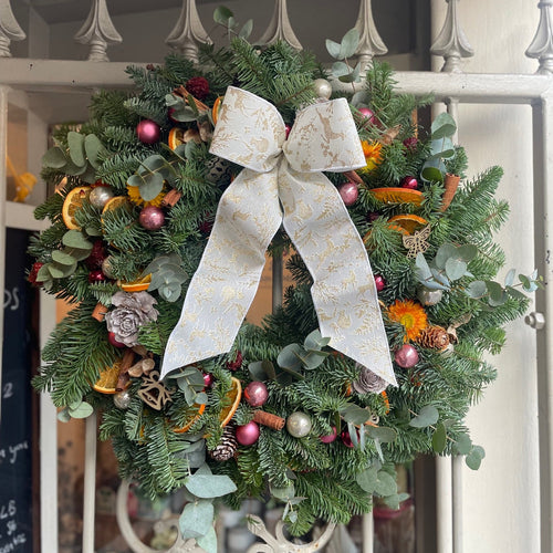 Decorative Christmas wreath with a large white bow on a door. bits and buds florist leighton buzzard