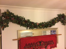 Load image into Gallery viewer, a scented decorated Christmas garland displayed above a fire place made from real foliage and spruce pine with dried fruit and cinnamon sticks to add a touch of luxury to your decorations from bits and buds florist in Leighton Buzzard.
