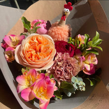 Load image into Gallery viewer, Bouquet of flowers with a toy chicken on top, set against a brown paper background. happy easter
