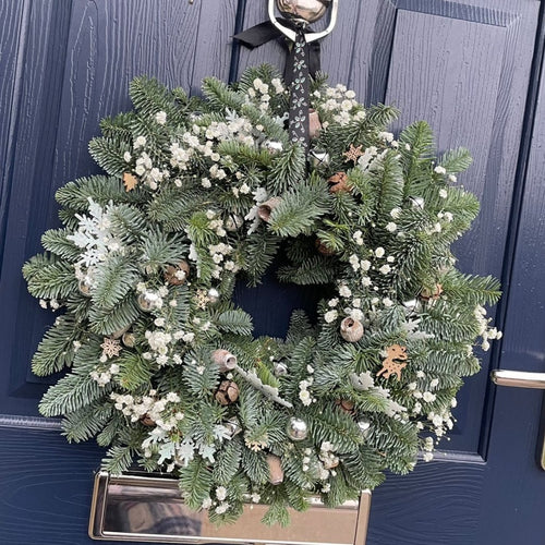 Christmas door wreath in elegant white and green with jingle bells and dried flowers